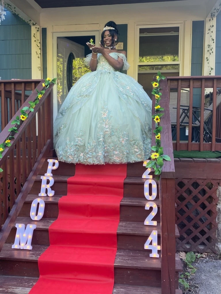 Prom 2024 in sage green ball gown with red carpet stairs