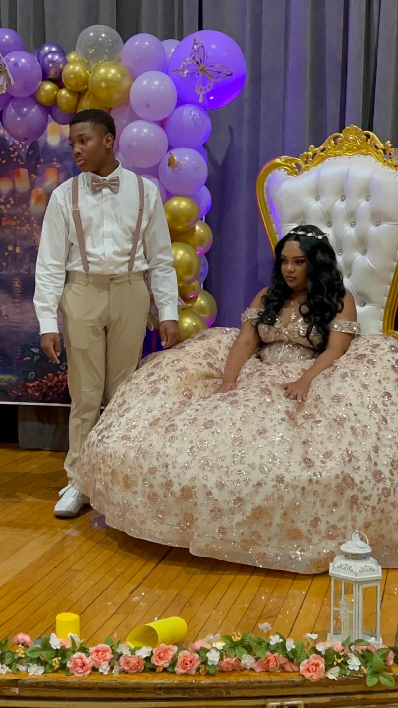 Quinceañera in rose gold gown with chambelan and purple balloon decor