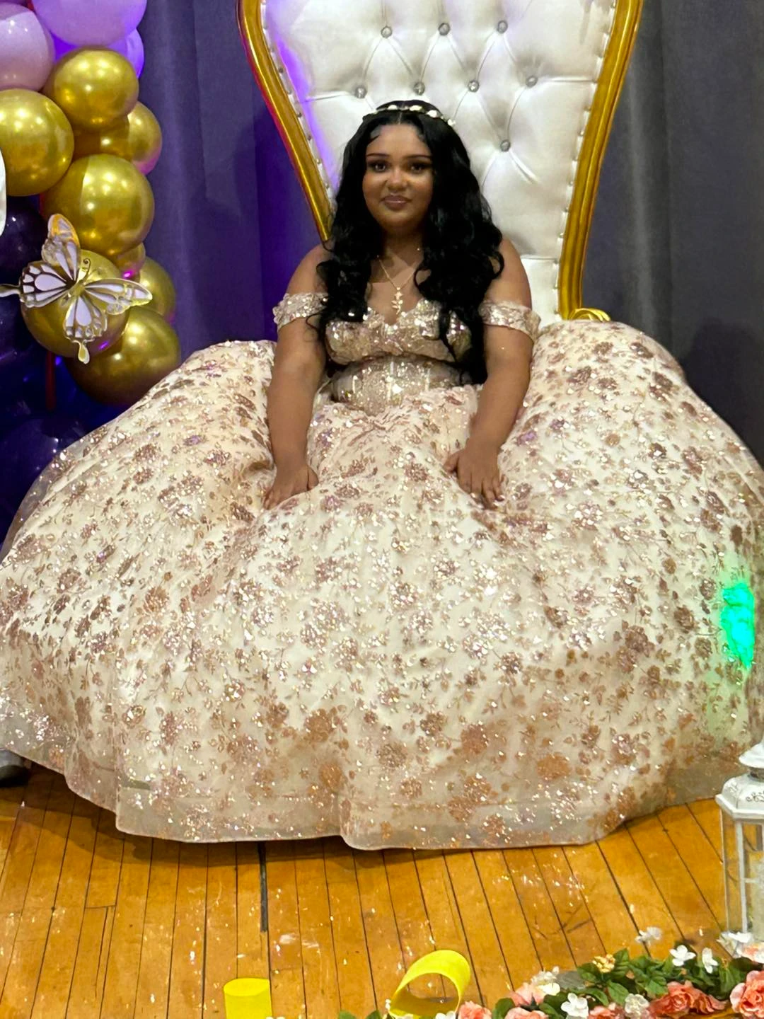 Quinceañera in rose gold gown on throne with butterfly decor