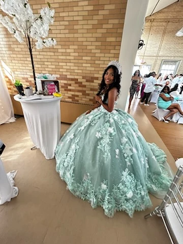Quinceañera in mint green floral ball gown at reception venue