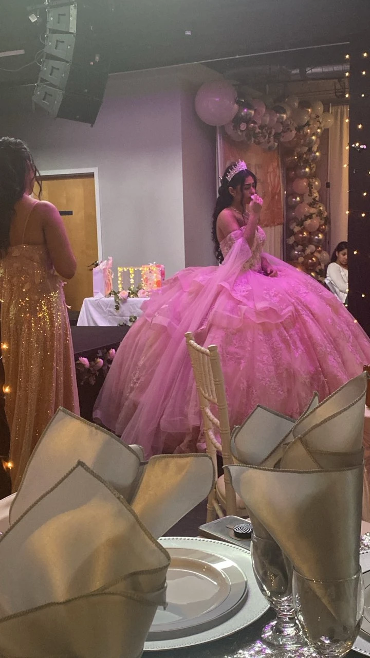 Quinceañera in pink ball gown at reception with balloon decor