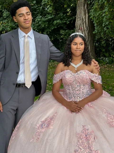 Quinceañera in pink ball gown with chambelan in outdoor portrait