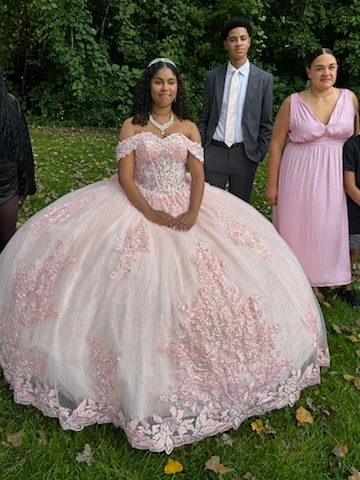 Quinceañera in pink ball gown with court outdoors