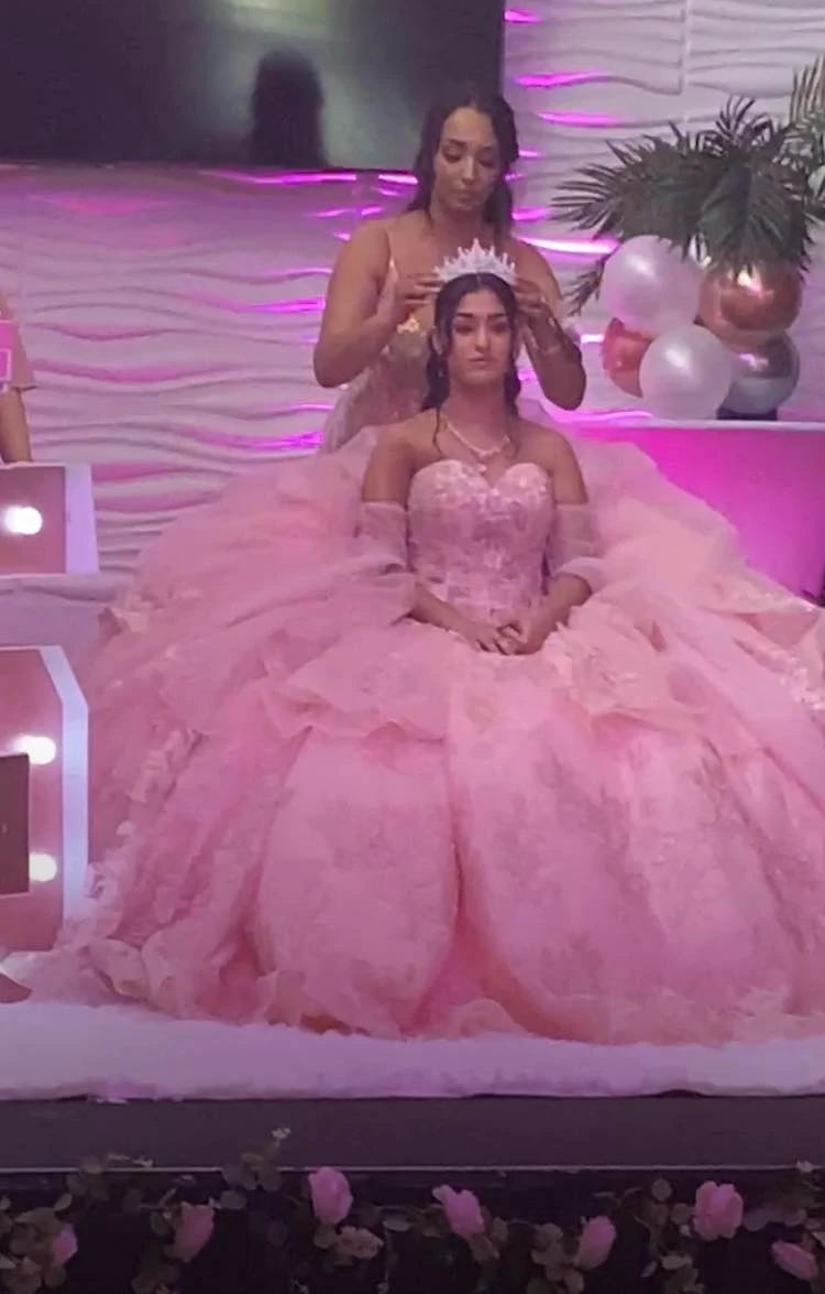 Quinceañera crowning ceremony in pink ball gown on stage