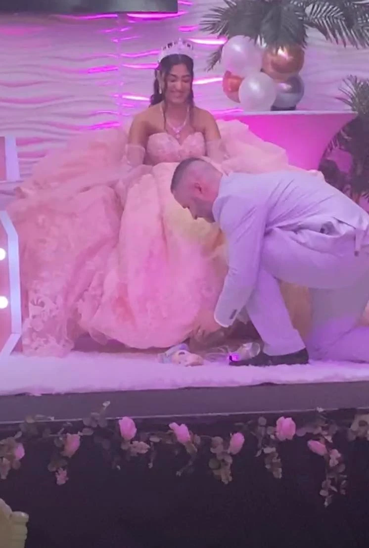 Quinceañera shoe ceremony in pink ball gown on stage
