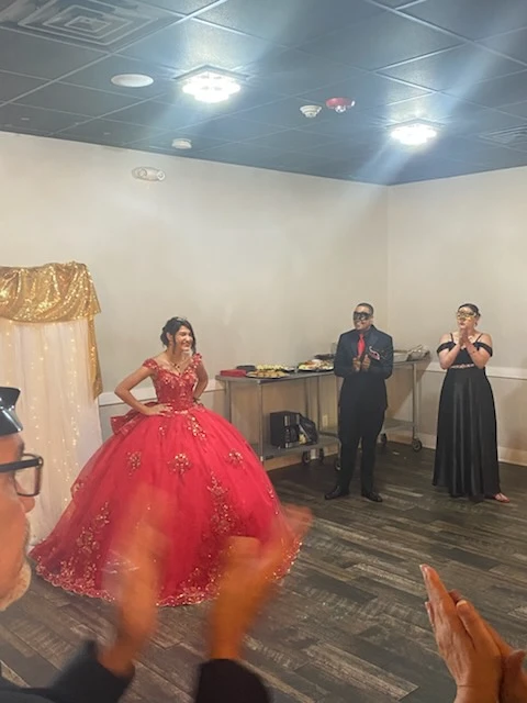 Quinceañera grand entrance in red ball gown with gold accents