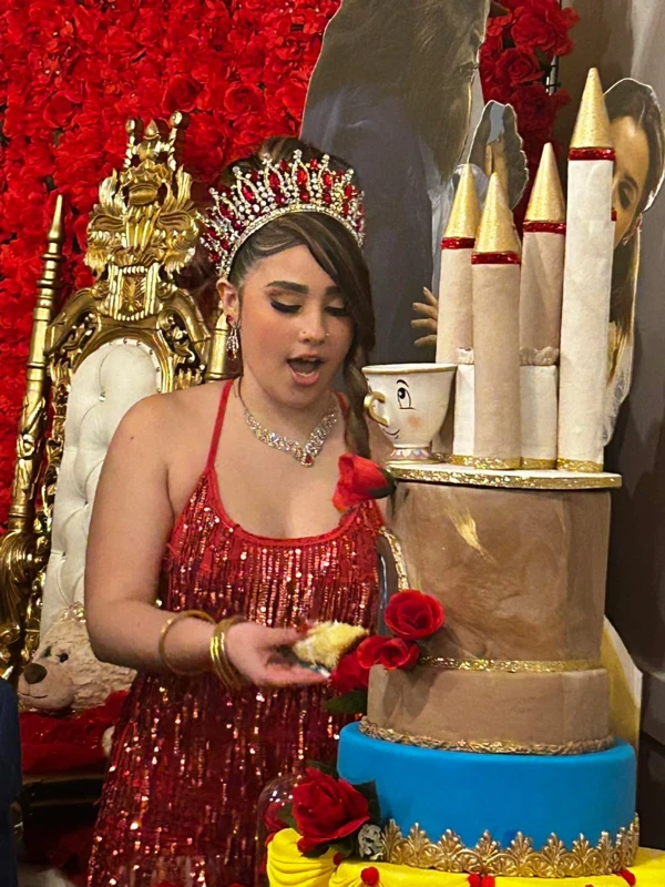 Quinceañera with Beauty and the Beast themed cake in red dress