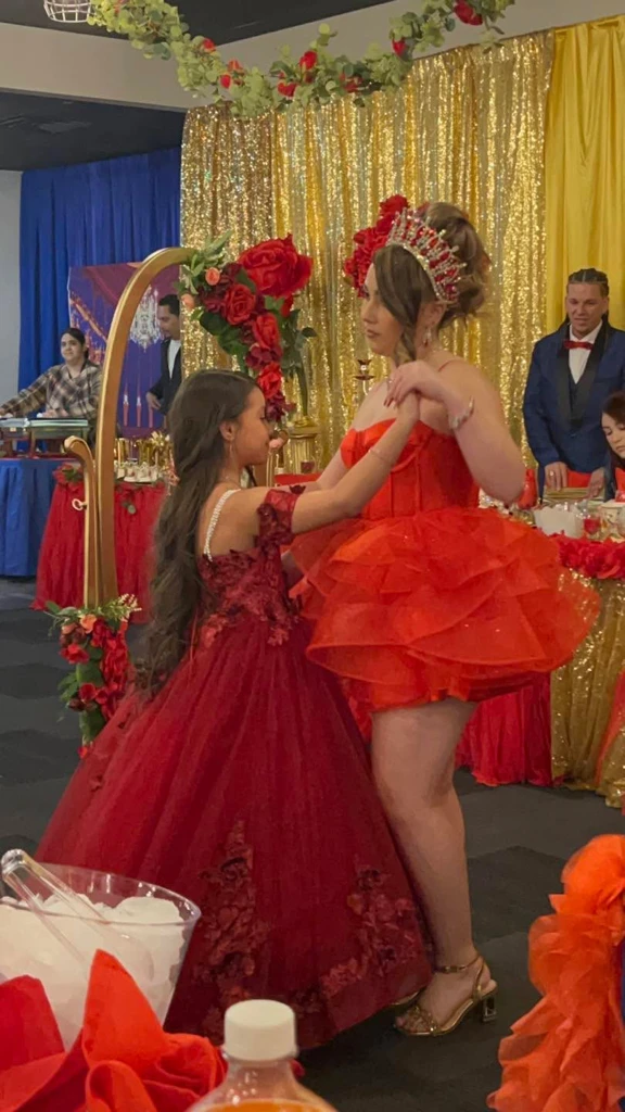 Quinceañera dancing with flower girl in red dresses