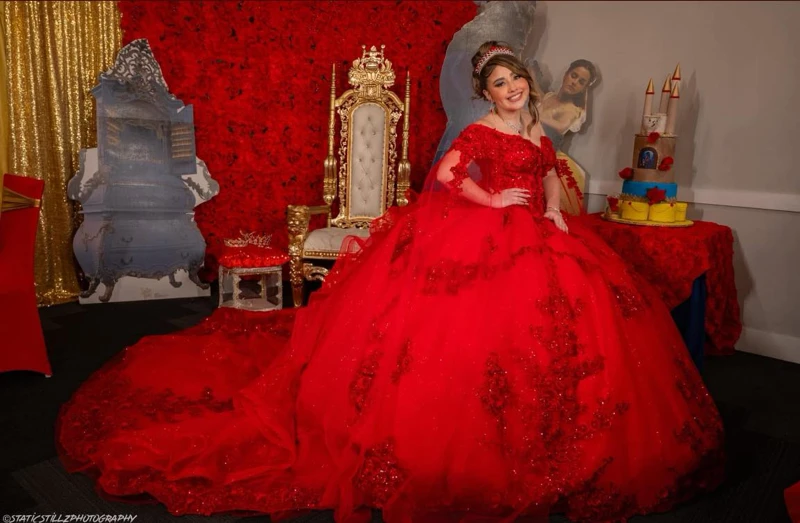 Quinceañera in red ball gown with Beauty and the Beast themed decor