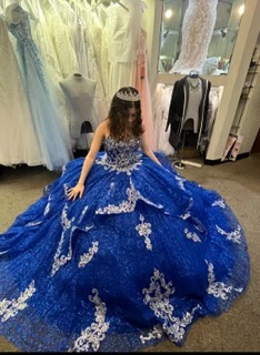 Quinceañera trying on royal blue ball gown with silver appliques