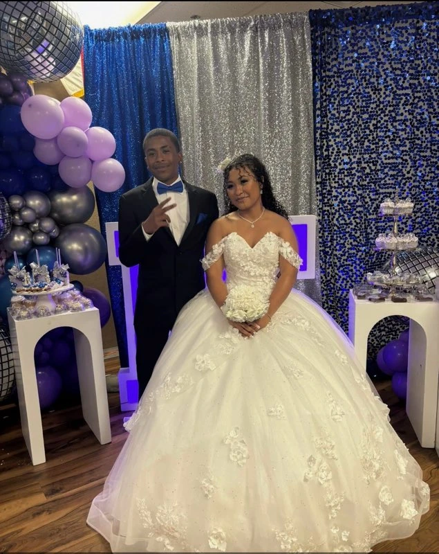 Quinceañera in white floral ball gown with silver and blue decor